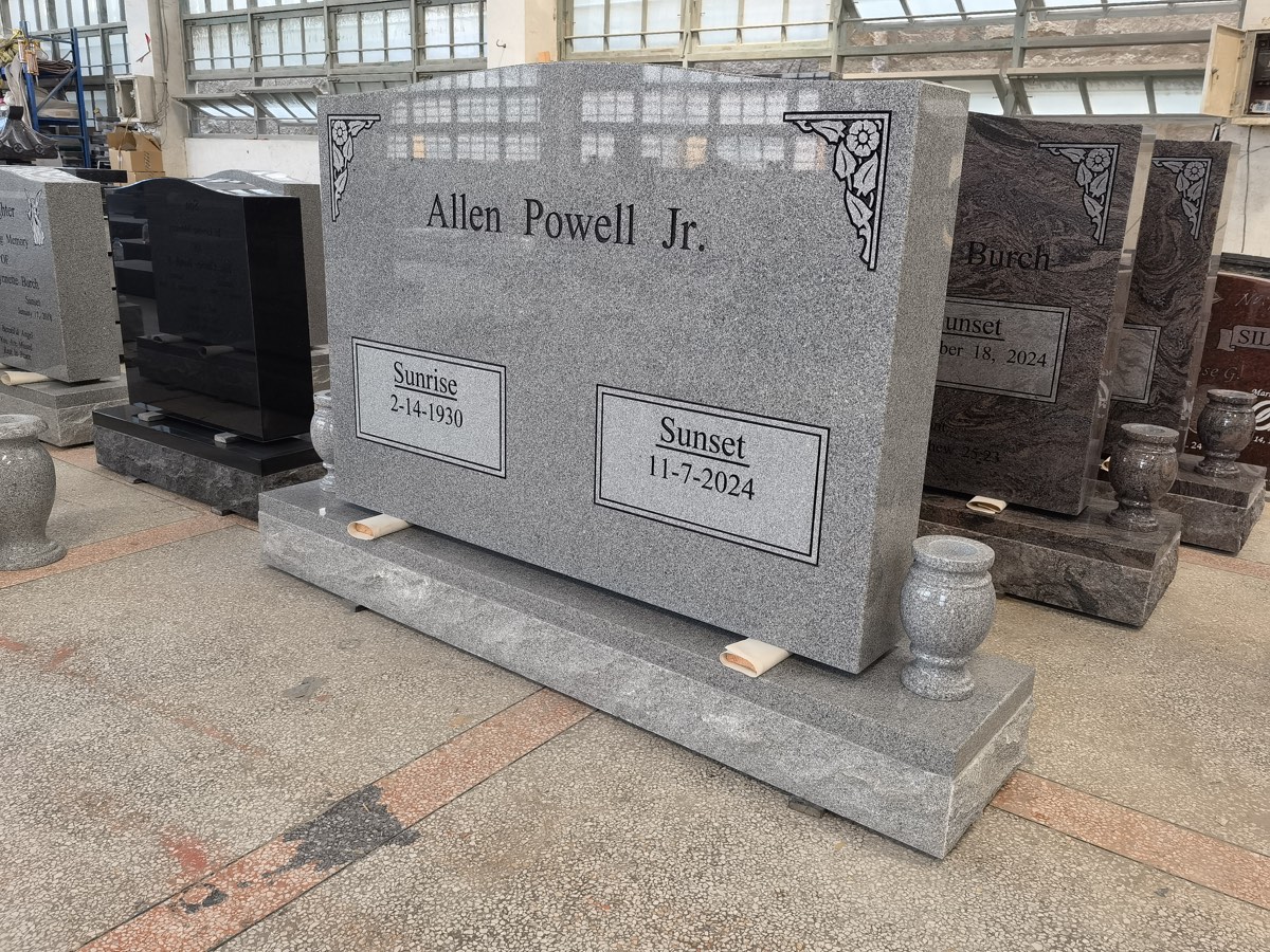 Gray granite memorial with dark lettering, floral corners and bordered date panels