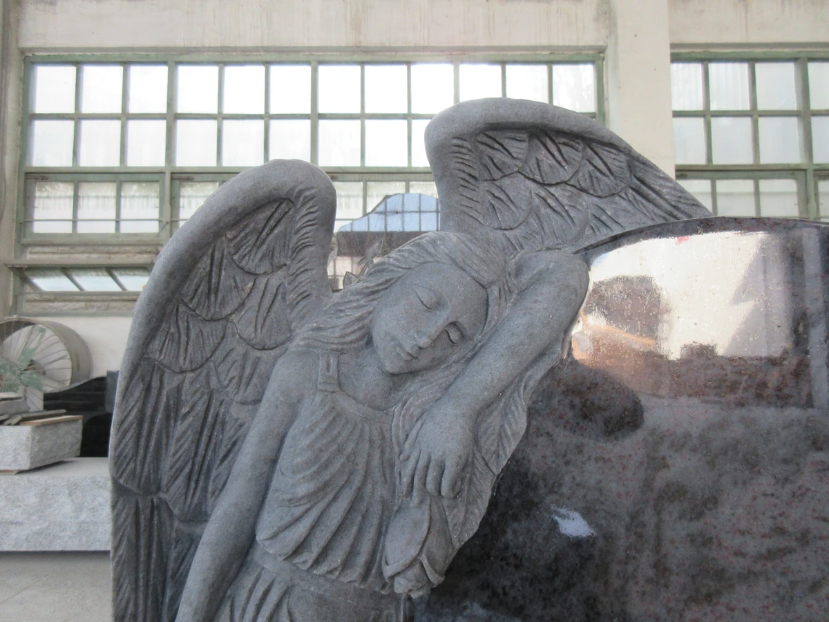 Carved angel wing, hair and drapery in granite