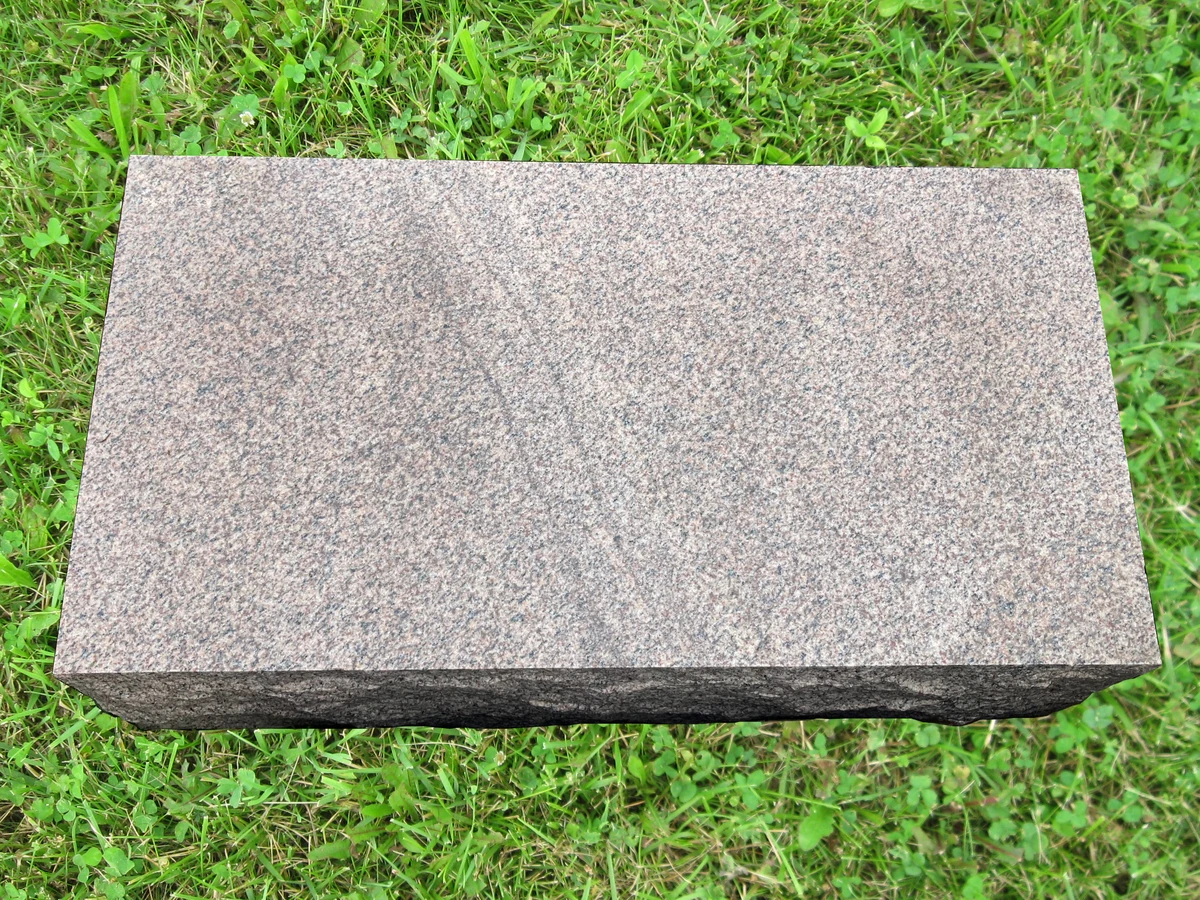 Low bevel granite marker with rock-pitched sides and a polished inscription face